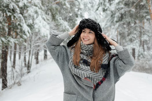 A cheerful woman in a winter coat and scarf enjoying a snowy day in a forest. Introduction to Winter Fashion Trends