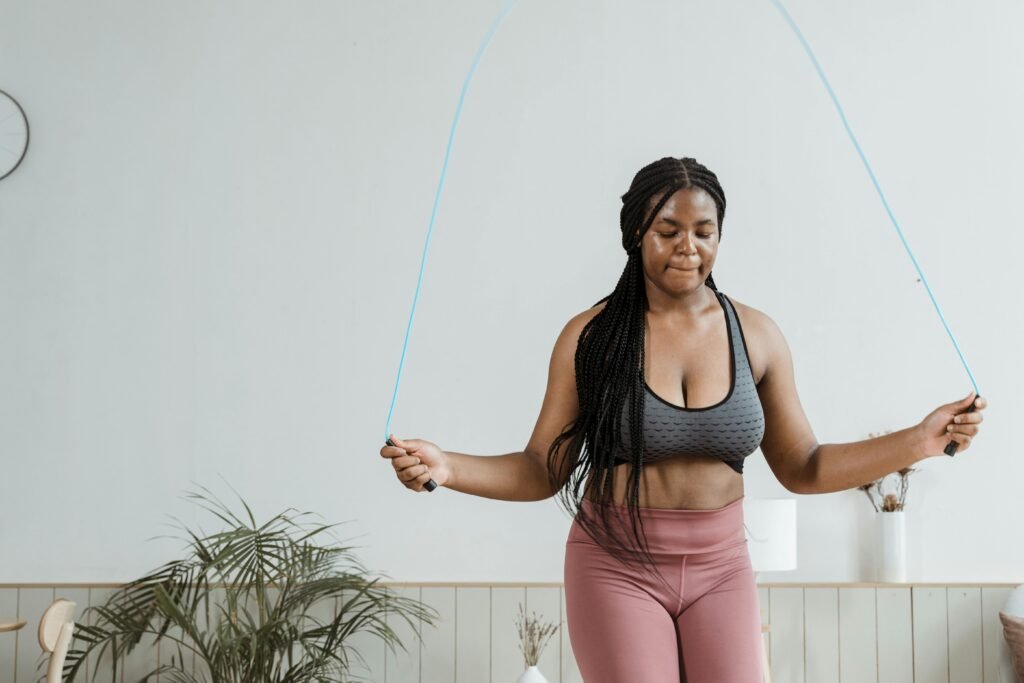 Fit woman in activewear jump roping indoors, promoting fitness and health.