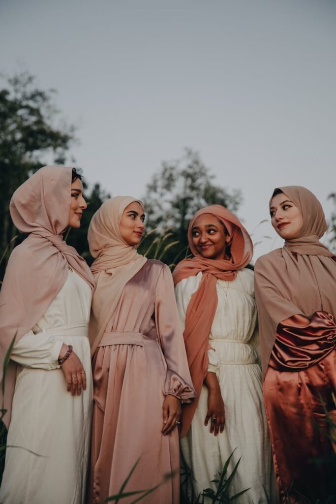 four women in hijab smiling and looking at each other